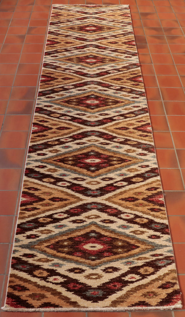 A diamond pattern going through the length of the rug using cream, toffee, dark brown, green and red.  There are some areas of geometric pattern work on some of the bands of colour used to make up the diamond shapes. 