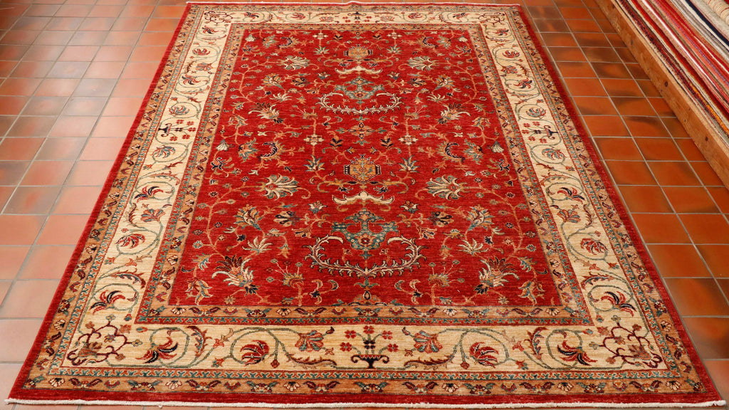 The tomato red background and the cream border makes this quite a light coloured rug overall, but with a rich warmth coming from the red. The classic pattern of stylized flowers in a palette of green, red, dark blue, with hints of peach and burgundy. It has a simple curvilinear design in the border.