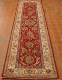 Russet red central ground with flora and fauna decoration through the length.  There is a central motif which is circular,  and two further circular motifs at either end.   The colours used within the colour palette for the decoration are green, blue, yellow, cream, and a soft orange.  There is a broad cream border with floral decoration again using the same colours.   