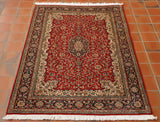 A rich red is the predominant colour with a cream edge to the main section of this rug.  There is a dark blue border with narrower contrasting borders to either side.  All of these areas have detailed decoration using flora and fauna as the main design.  The additional colours in the palette are greens, blues, orange and browns. 