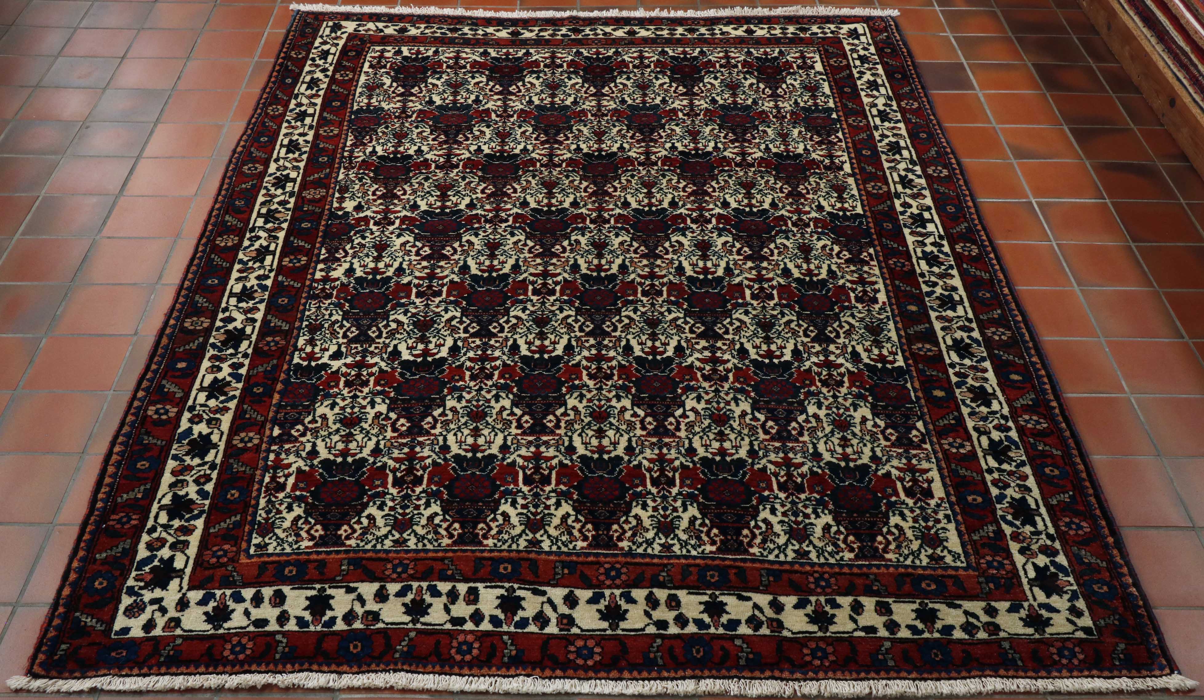 The central section to this rug is complex.   There are bands of cream floral motifs with green, yellow and red used to show the floral aspect.  between each is a dark blue and red vase shape.  Around the edge of the rug are three borders, each with a floral pattern, the middle one having a cream ground, whilst the others are a deep red/orange ground. 