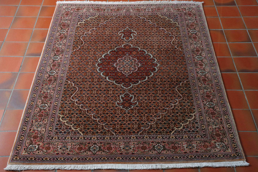 This Fine Persian Tabriz measures 150 by 105 centimetres.  The central medallion in a deep soft pink and is surrounded by a sophisticated design, something similar to designs seen at the Alhambra Palace in Andalucia. The colours used are all very soft and include a pink, peach, gold, green and rust, and the design being interwoven florals and small singular flowers. 