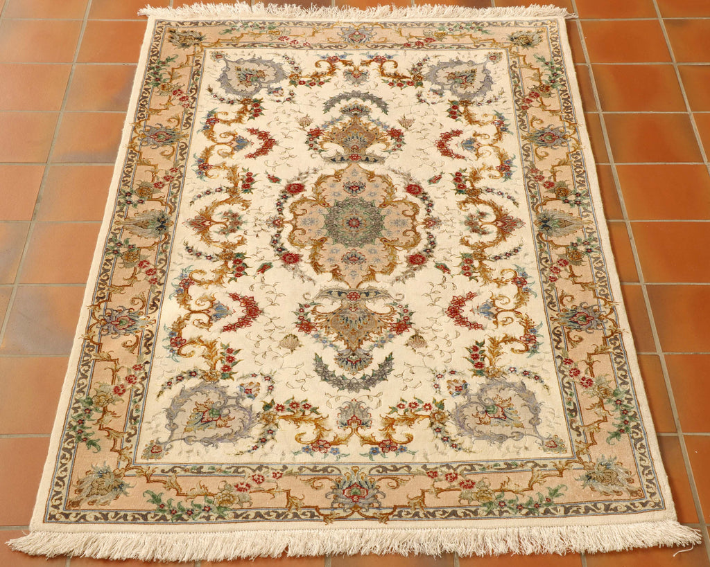 A soft cream central ground with a striking floral design using a colour [palette of red, golden yellow, olive grren, brighter greens, blues of multiple shades.  There is a central motif  with smaller motifs in each cornere.  Around the edge in a wide border in a soft yellow/cream can be found additional decoration using the same colour palette and complimenting the design work in the main of the rug.  