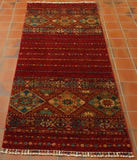 Afghan Samarkand runner in a soft red with teal, mixing traditional designs with modern elements. accents colours include yellow, green, gold and dark blue.