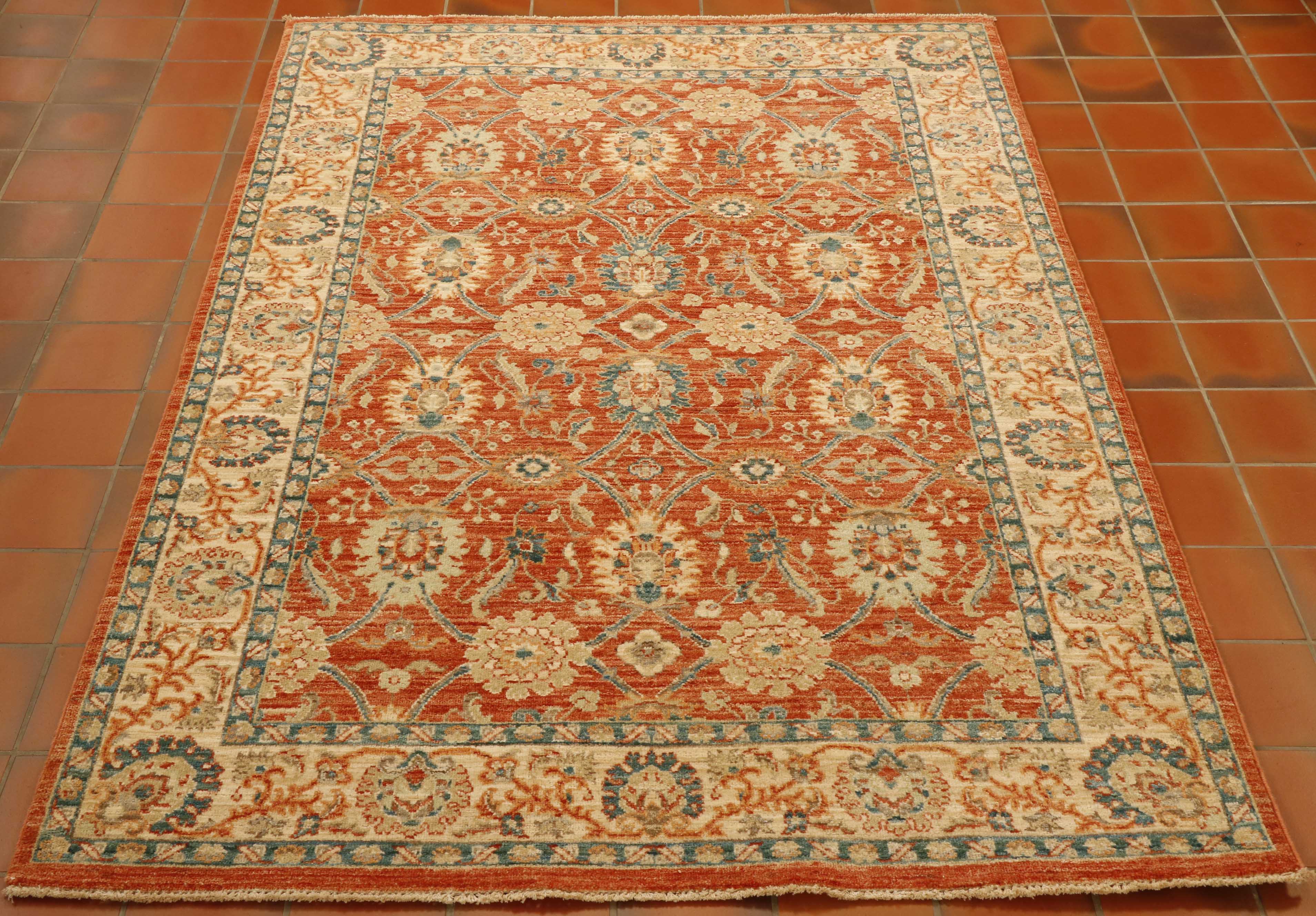 Soft terracotta ground with a blue and cream decoration of flora. Cream border with similar floral design but using the terracotta and blue as the colour palette. Soft green used for highlights.