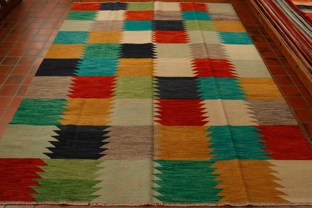 Kilim rug 299 by 209.  A large rug with a striking, chequer board design.   The rug is broken down into squares with a colour palette consisting of various shades of golden yellow, rich red, deep blue, turquoise, leaf green, pale sea blue, cream and a soft fawn. 