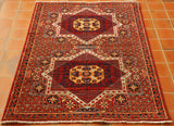 Two large star medallions in the central section.  Surrounding these small flowers laid out evenly across the rug.  The main ground is a warm rich red,  with a golden yellow, dark blue and soft blue used in the decoration